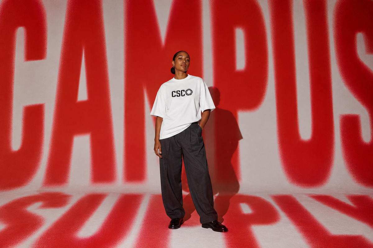 Woman wearing a white CSCO T-shirt against a red Campus Supply projection